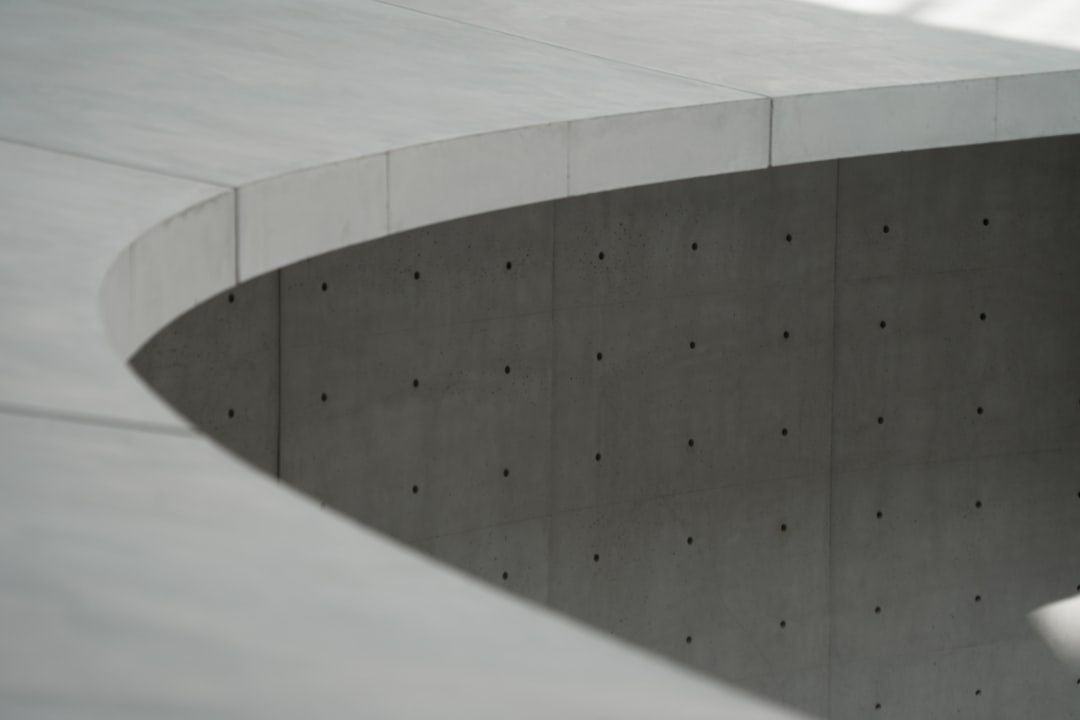Nahaufnahme einer monolithischen Sichtbetonfassade mit gebogenen Linien